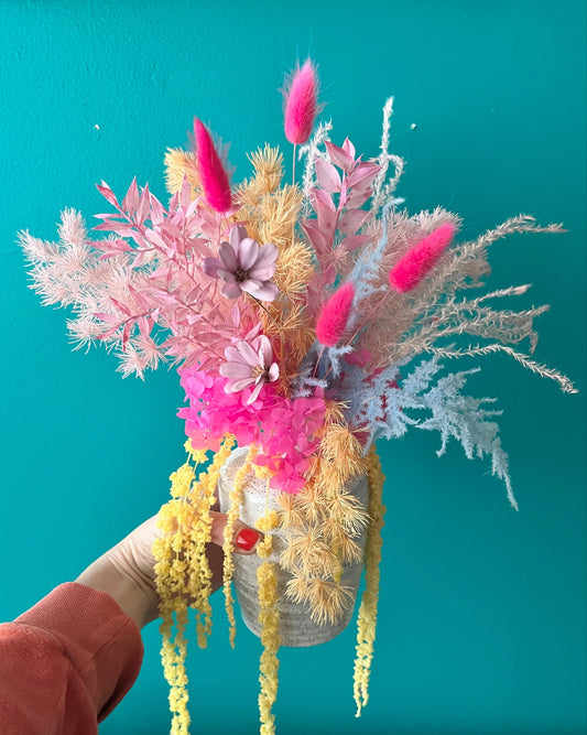 Bouquet of colorful dried flowers held against a teal background